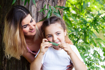 young pretty mother walking with little cute daughter outside in green park, lifestyle poeple concept