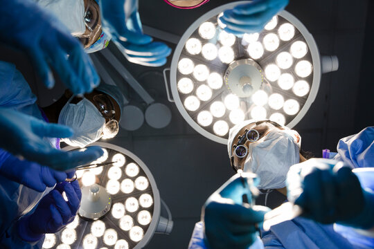 POV surgeons performing surgery below lights in operating room