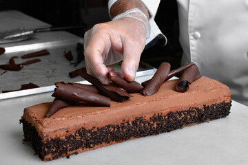 The pastry chef's hand places chocolate chips on the cake