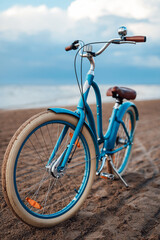 Fototapeta na wymiar Light-blue bicycle on the beach with the sea on the background
