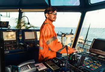 Filipino deck Officer on bridge of vessel or ship wearing coverall during navigaton watch at sea ....