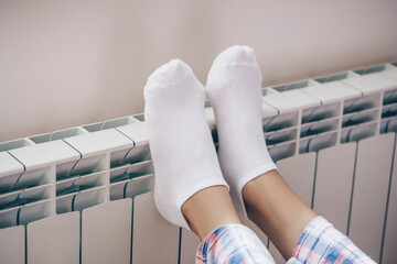 Woman laying on floor with feet raised up on radiator for warming up

