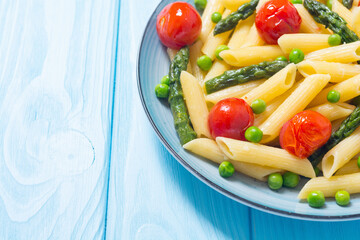 Penne pasta salad with asparagus , tomatoes and peas