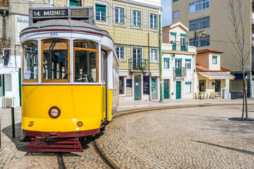 Fototapeta na wymiar The yellow 28E tourist tram in the Graça neighbourhood of Lisbon, the capital of Portugal