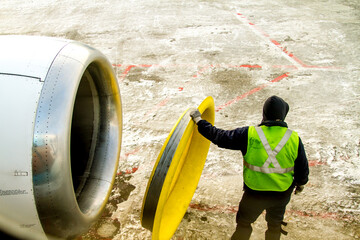 An airport worker is placing a heat retention shield on a jet engine on a very cold winter morning...