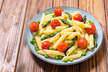Penne pasta salad with asparagus , tomatoes and peas