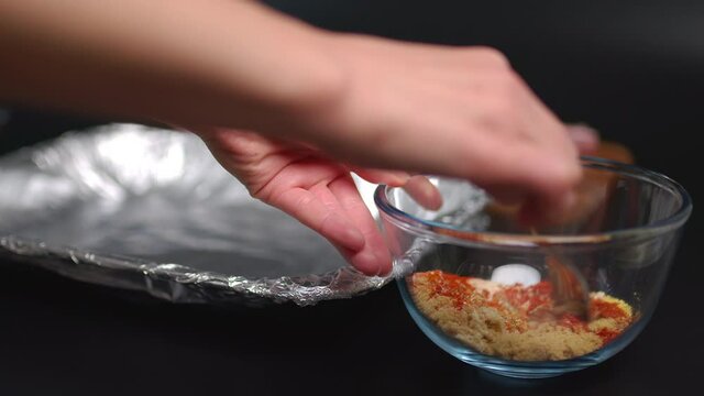 Grilled ribs marinating spices in a transparent glass bowl in 4K. Brown sugar, chili powder, sweet paprika, salt, dry mustard, garlic powder, onion powder, ground pepper.