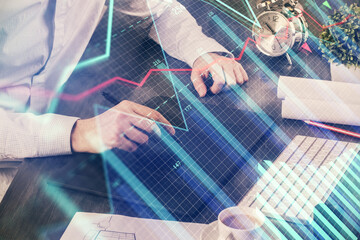 Double exposure of man's hands holding and using a phone and financial graph drawing. Analysis concept.