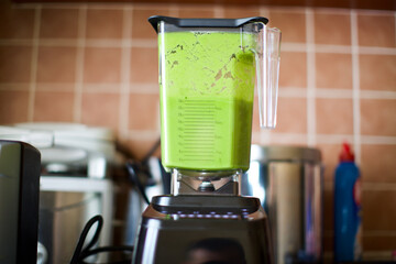 fruits prepared for making smoothies in the blender. It contains spinach, kiwi, pineapple, apple and orange.