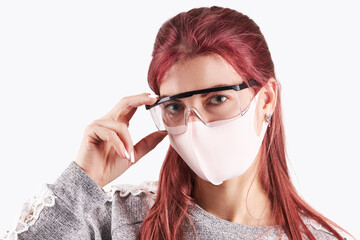 studio portrait of a young caucasian woman wearing protective face mask and goggles. isolated on a gray background. copy space