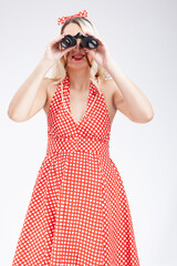 Pin-up Girl. Caucasian Blond Girl Posing in Pin-up Style. Holding Binoculars in Front of Her Face and Watching. Against White.