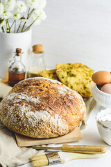 Homemade sourdough bread and flatbread, some eggs, oil, sesame, white background.