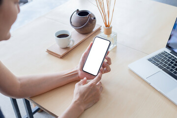 cell phone mockup image blank white screen.woman hand holding texting using mobile on desk at coffee shop.background empty space for advertise.work people contact marketing business,technology