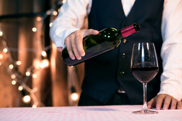 Waitress man pouring wine into glass