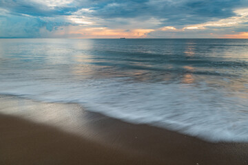 Fototapeta premium Virginia Beach on a calm cloudy morning, waves crashing on sand