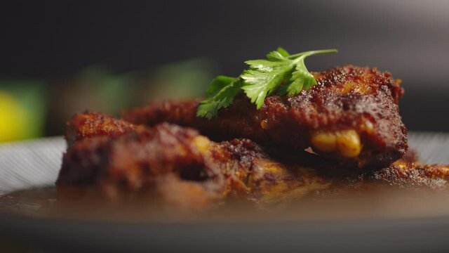 Grilled ribs in a serving plate on a wooden table with a black background in 4K. Concept of serving ribs that fall off the bone.