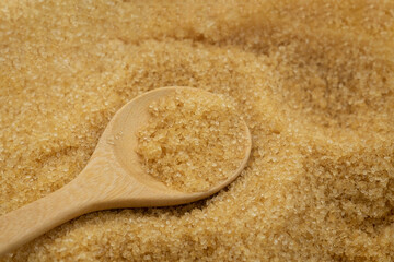 Wooden spoon on pile brown cane sugar texture background. Raw natural, Organic cane sugar for healthy.