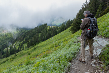 Mature male checking the elevation on his cellphone while hiking near the top of Mt. Sauk in Washington. 