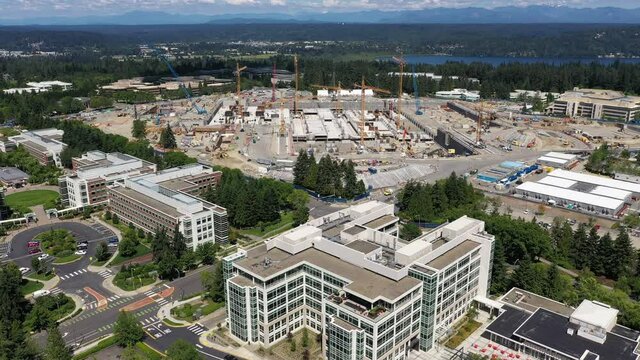 Drone footage of construction in Redmond, Washington at the Microsoft corporate headquarters with Lake Sammamish and the Cascade range as a backdrop