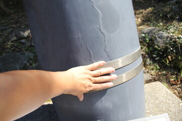 金属製の円柱を触る手