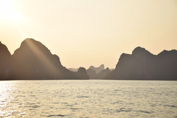 Naklejka na ściany i meble Halong Bay (UNESCO World Heritage) during a cloudless sunset with outlines of the beautiful karst landscape, Vietnam