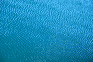 Fototapeta na wymiar Ripples on blue water, diagonal perspective view, soft low contrast image.