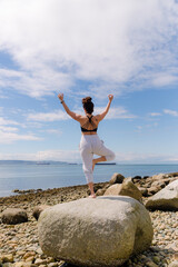 young woman doing yoga exercises on the beach