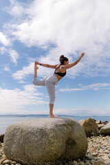 young woman practicing yoga on the beach