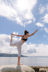 Obraz premium Young woman in yoga pose on the beach
