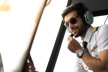 Portrait of commercial pilot in uniform sitting inside helicopter cabin.