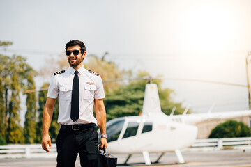Portrait of helicopter pilot in uniform walk and standing outside with private helicopter background © NVB Stocker