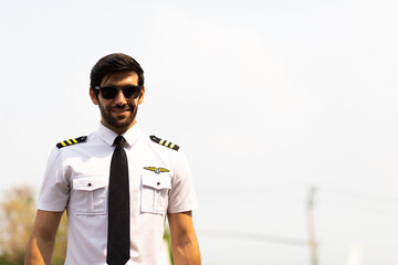 Portrait of helicopter pilot in uniform walk and standing outside with private helicopter background