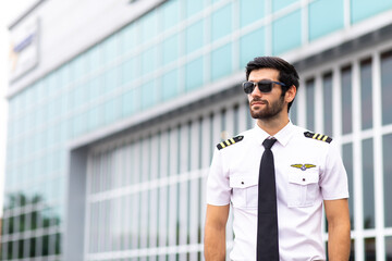 Portrait of helicopter pilot in uniform walk and standing outside with private helicopter background