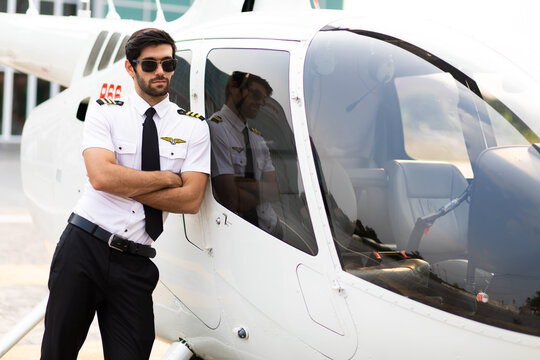 Portrait of helicopter pilot in uniform walk and standing outside with private helicopter background