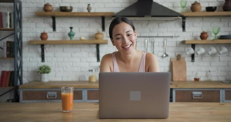 Healthy Asian woman has video call on laptop and drinking orange juice