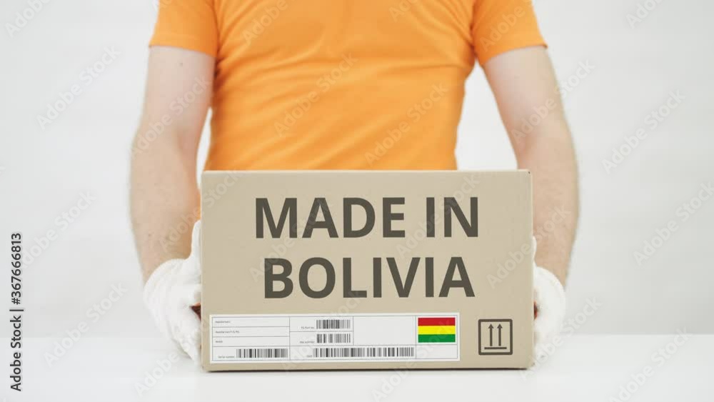 Aufkleber man puts cardboard box with made in bolivia text on the table
