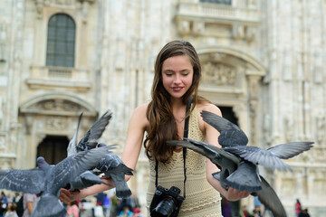 Obraz na płótnie Canvas Milan, Italy. Happy tourist in front of Duomo cathedral. Travel tourist woman feeds doves near Duomo di Milano. Funny girl with dove sitting between them.