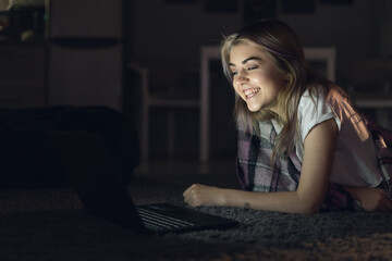 young beautiful woman at night watching a movie on a laptop. Cinema online.