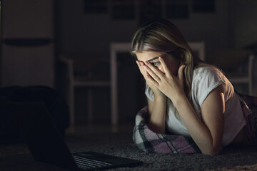 Obraz premium young beautiful woman at night watching a movie on a laptop. bedtime horror movie