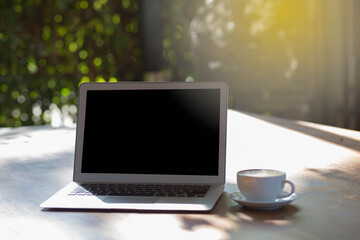 Blank screen laptop and coffee on the table in garden