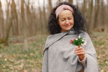 Woman in a forest. Adult lady walks. Woman with bouquet of flowers.
