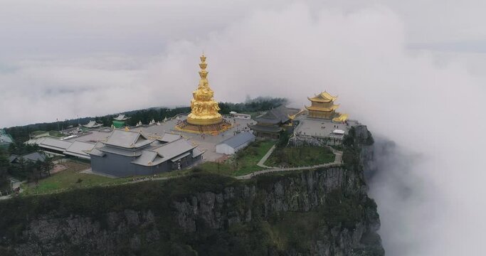 Aerial top view of Emei Jinding Emei mountain in the mist by the cliff with clouds floating moving in the sky 4k nature landscape in Sichuan China 