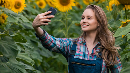Gorgeous, young, energetic, female taking a picture with herself in the middle of a beautiful sunflower field.