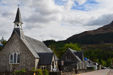 Fototapeta na wymiar Glencoe street with church set against mountains in the Scottish Highlands.