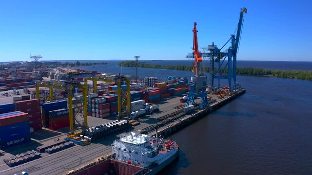 Aerial view of a row of construction or cargo cranes on the river bank. Ship docks off Kanonersky Island. Industrial port with water barges and transport tugs.