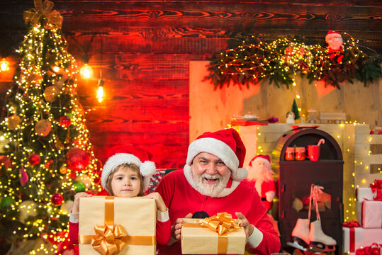 Funny little Santa father and son holding bag with presents. Santa child grandfather and grandson . Boy child play with real Santa near christmas tree.