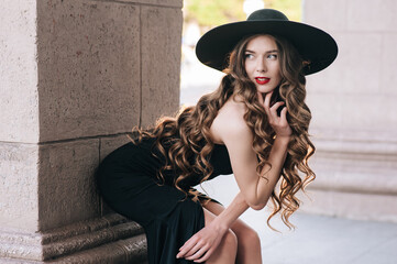 Ukrainian girl in a black dress outdoors in a hat