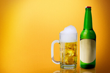 Beer bottle and glass of cold beer with a yellow background