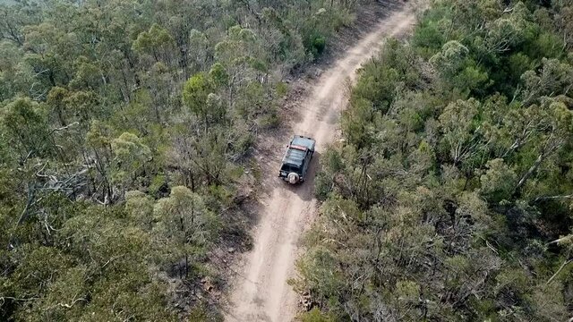 Drone footage of Blue off-road vehicle driving on dirt road in Australian bushland Victoria High Country after fires.