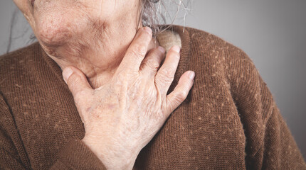 Elderly woman touching the neck feeling sore throat pain.